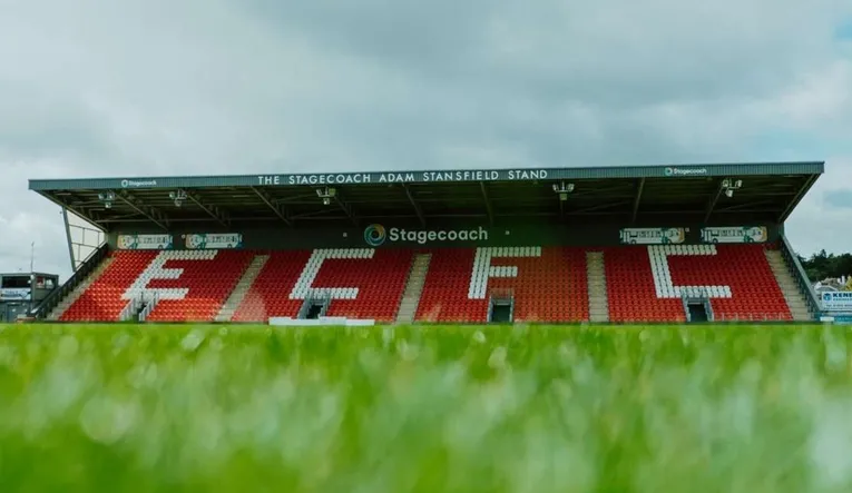 Cận cảnh khán đài Stagecoach Stand tại sân St. James Park, Exeter, với hàng ghế thẳng hàng và tầm nhìn rõ ra sân.