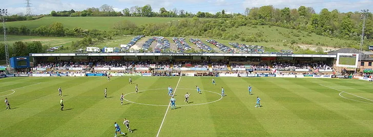 Cảnh cầu thủ Wycombe Wanderers và Notts County thi đấu trên sân Adams Park, với khán giả trên khán đài