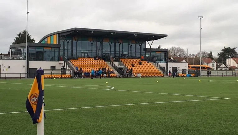 Khán đài chính (Main Stand) của sân vận động Arbour Park, Slough, với các hàng ghế xanh